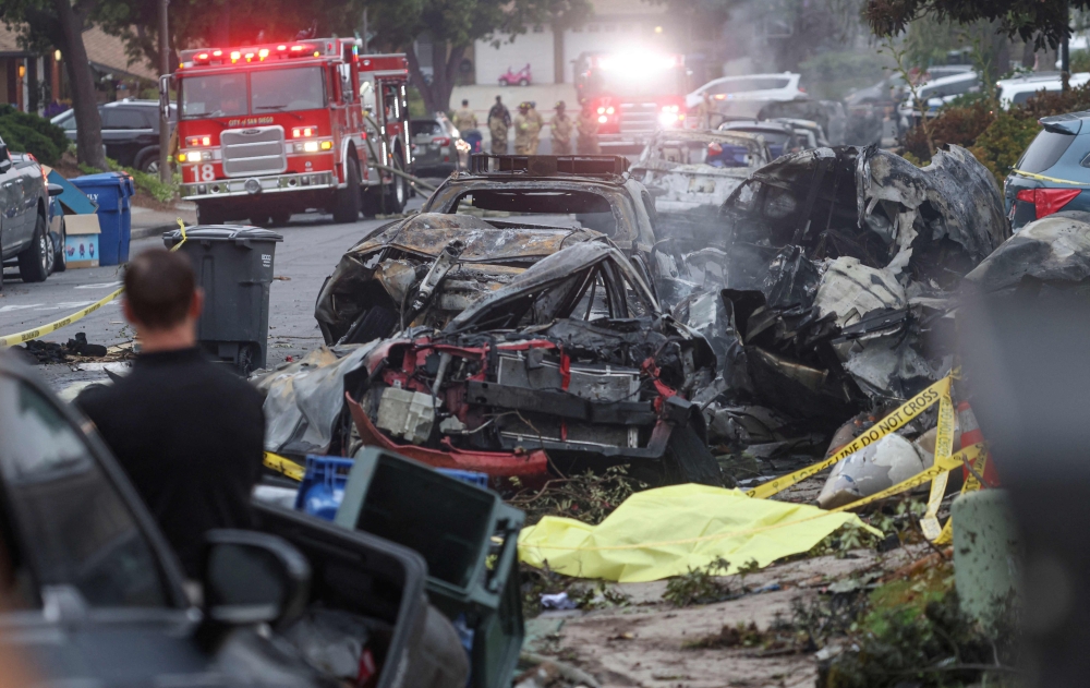 278451 Investigators look through the site where a small plane crashed on a San Diego, California, residential street on May 22, 2025. The crash left a ‘gigantic debris field’ and damaged some 15 homes and parked cars, ABC News quoted the San Diego assistant fire chief as saying. — AFP pic
