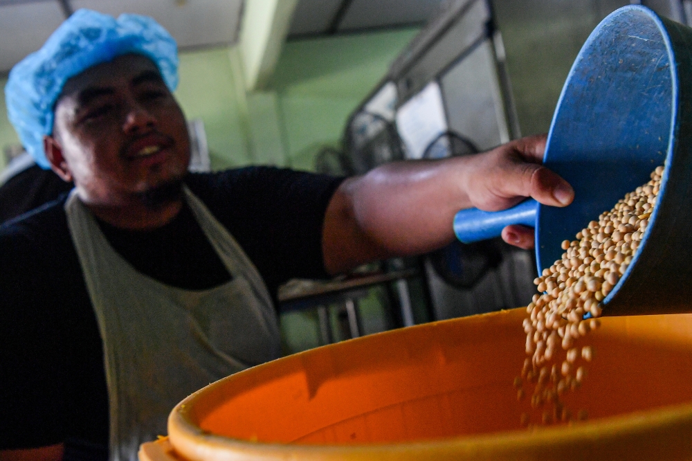 278644 Worker Muhammad Haziq Maceri measuring soybeans before placing them into a grinder at the Mie Soya Enterprise factory in Taman Jujur, Sikamat, recently. — Bernama pic