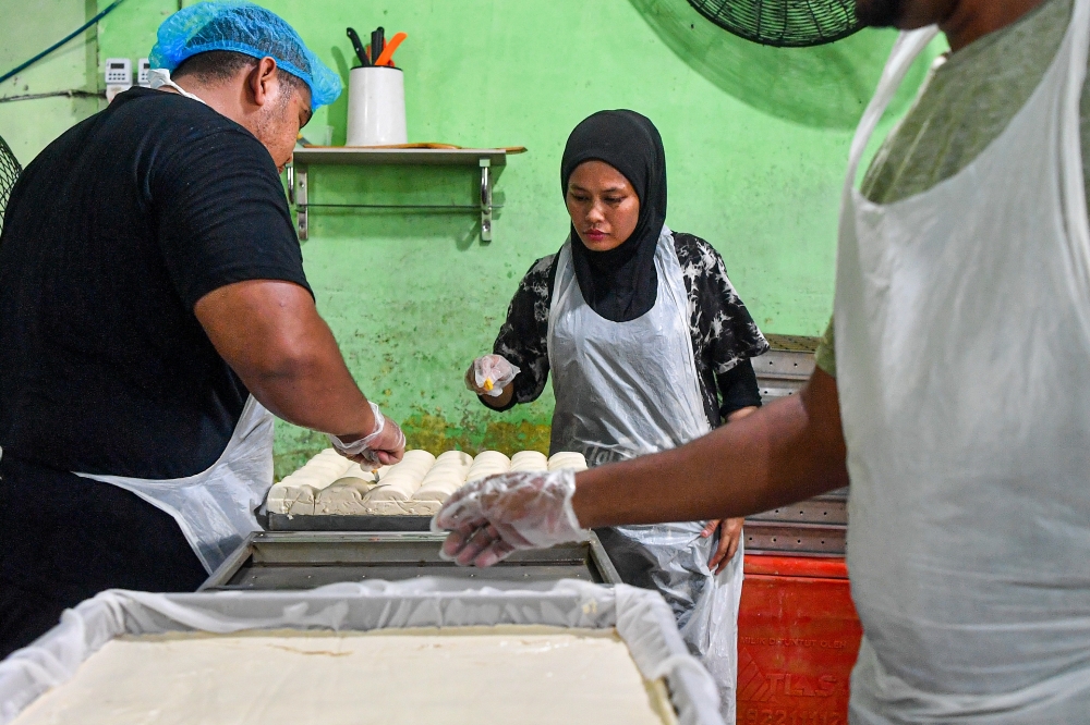278645 Mie Soya Enterprise worker Siti Faizah Hamdan (centre) cutting tofu blocks during the production process at the factory in Taman Jujur, Sikamat, recently. — Bernama pic