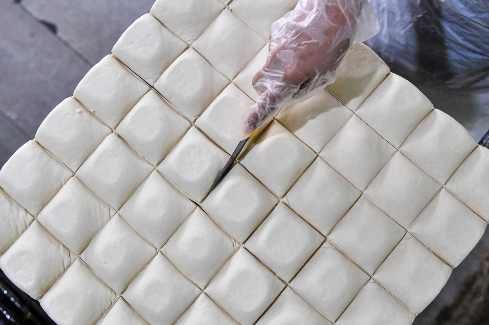 278647 Mie Soya Enterprise worker Siti Faizah Hamdan cutting tofu blocks during the production process at the factory in Taman Jujur, Sikamat, recently. — Bernama pic