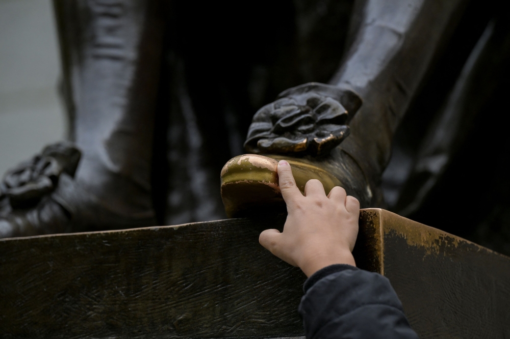 278785 A boy touches the foot of the John Harvard statue on the campus of Harvard University in Cambridge, Massachusetts, May 23, 2025. — Reuters pic