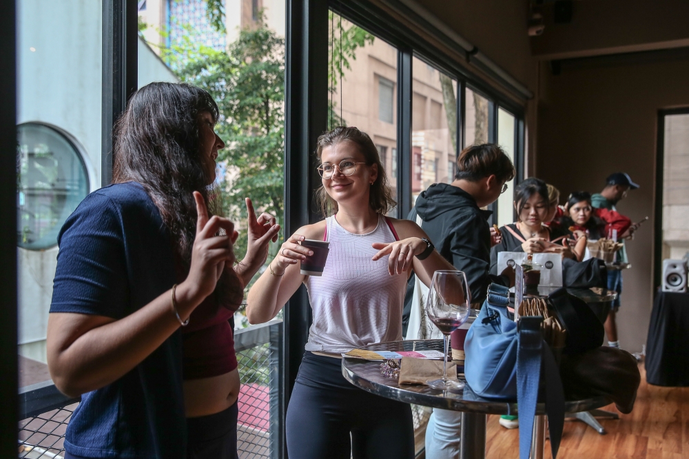 280152 Have caffeine, talk flows: Julia (white shirt) and Hershey (left) get into deep discussion during the coffee rave event at UP Kuala Lumpur on May 31, 2025. — Picture by Yusof Mat Isa