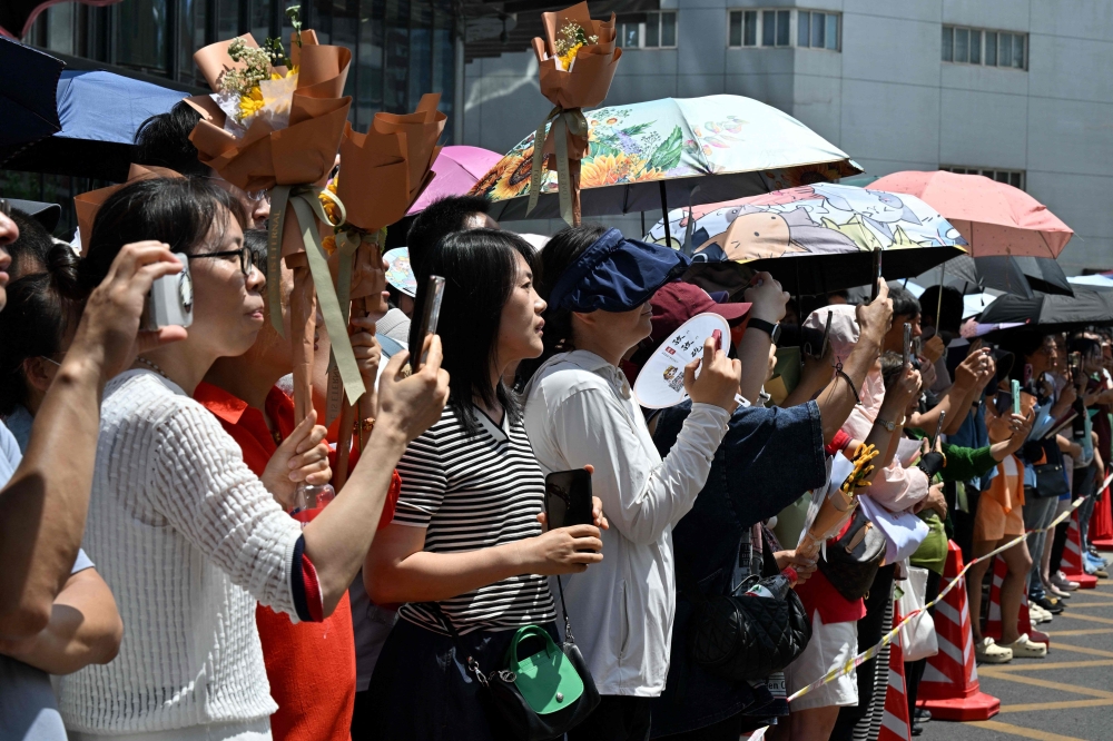 Parents wait for their children during the first day of China’s National College Entrance Examination. — AFP pic