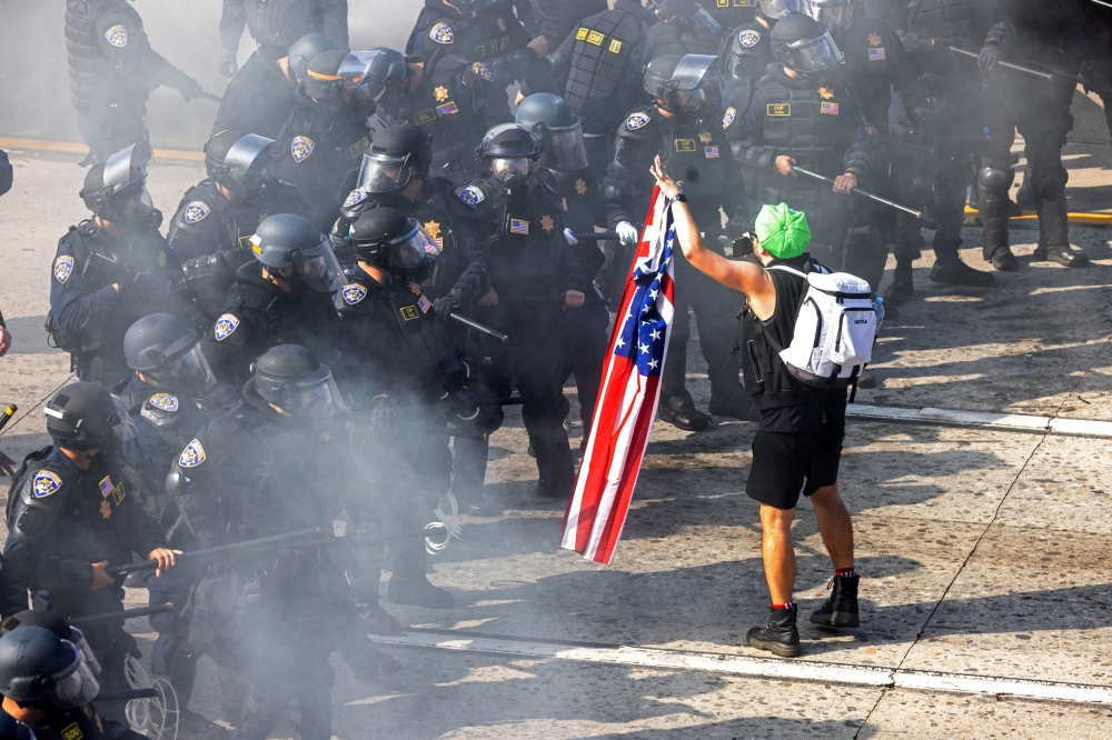 A demonstrator holds a US flag across from California Highway Patrol officers. — Reuters pic
