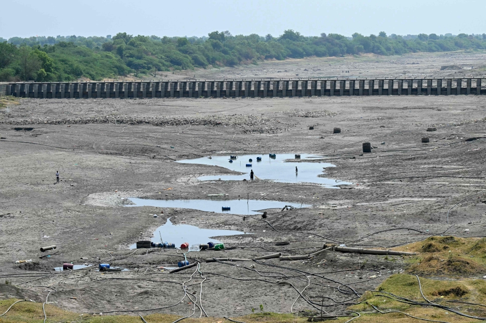 In this photograph taken on May 4, 2025, people walk across the dried-up Godavari river in Beed district in India’s Maharashtra state. — AFP pic