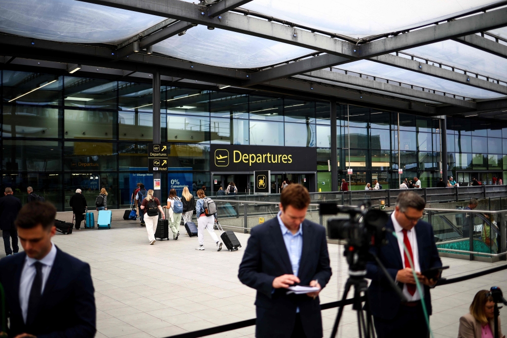 Members of the press gather outside the North terminal upper forecourt in front of the departure entrance at Gatwick Airport, south of London, in June 12, 2025 after a London-bound passenger jet with 242 people aboard crashed shortly after takeoff from India's Ahmedabad airport. — AFP pic