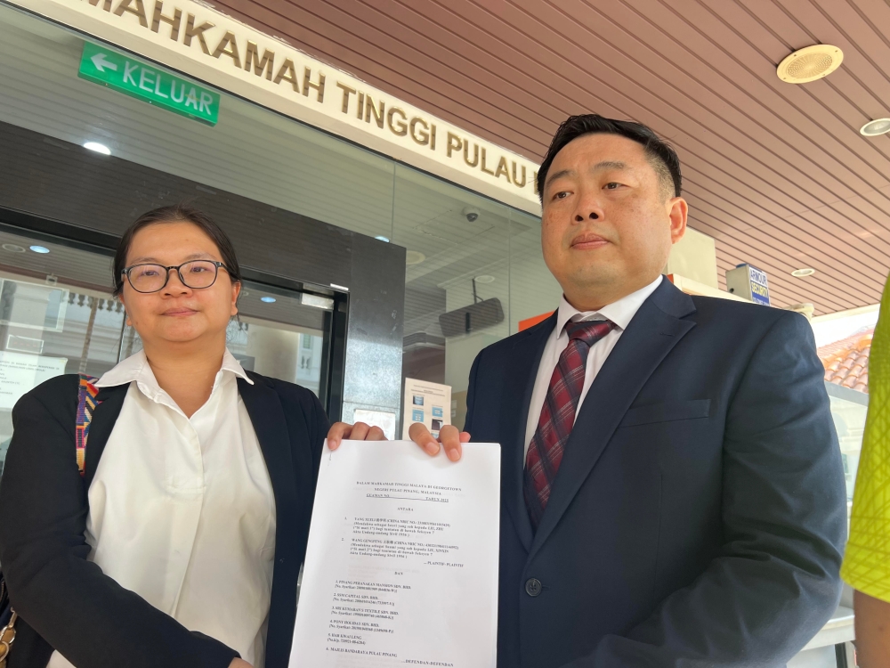 Ng Kian Nam (right) with the writ of summons and statement of claims at the High Court in Penang on June 13, 2025. — Picture by Opalyn Mok