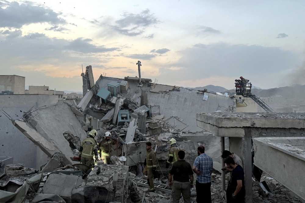 People and first-responders gather atop a building a that was hit by an Israeli strike in Tehran on June 13, 2025. Israel hit about 100 targets in Iran on June 13, including nuclear facilities and military command centres and killing senior figures including the armed forces chief and top nuclear scientists. — Tasnim News/AFP pic