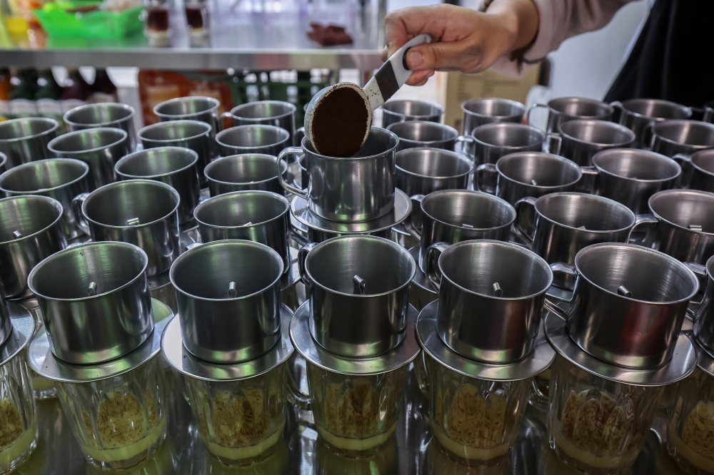 Ainun Hajar Kamaruddin prepares a measured serving of coffee for a customer during the new Kopi Tenggek Tanjung Piai outlet’s opening in Larkin June 15, 2025. — Bernama pic