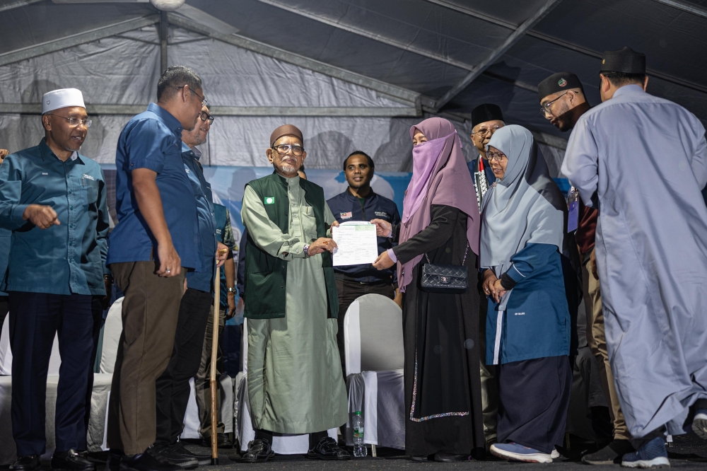 PAS president Tan Sri Abdul Hadi Awang receives a party membership form from Datuk Wan Norashikin Wan (3rd right) during the Perikatan Nasional mega rally ahead of the Ayer Kuning state by‑election at Tanjung Keramat Village in Tapah April 19, 2025. — Bernama pic