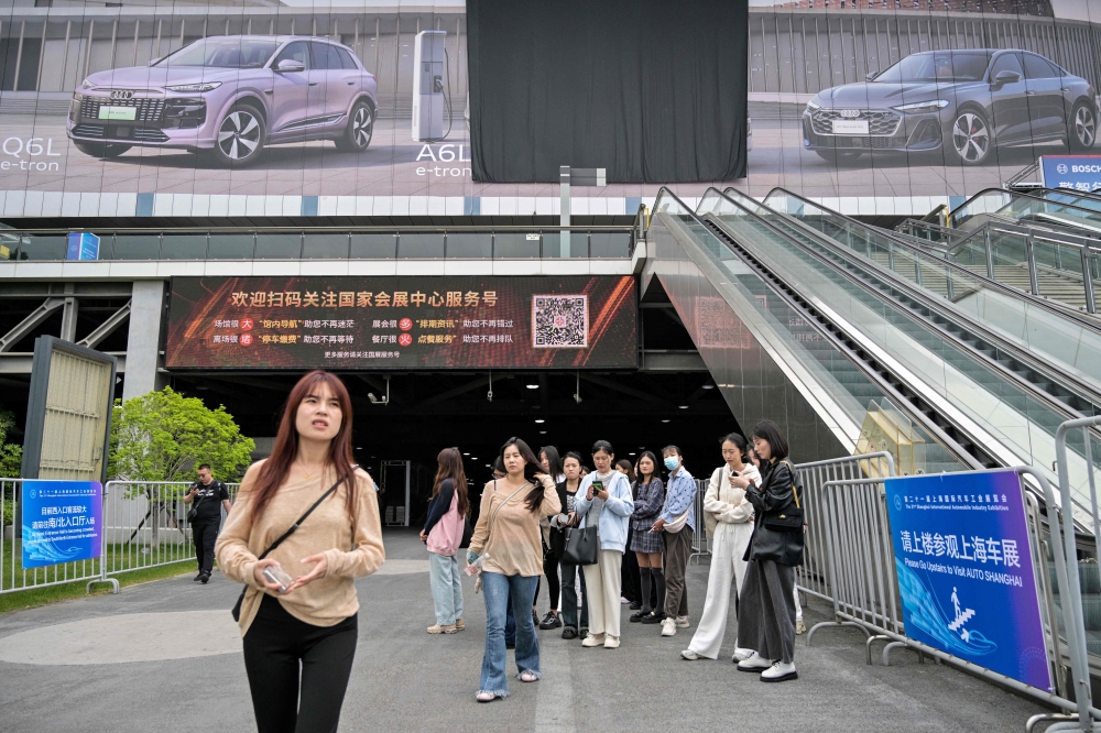 272550 People look on outside the National Exhibition and Convention Centre, venue for the upcoming 21st Shanghai International Automobile Industry Exhibition, in Shanghai April 21, 2025. — AFP pic