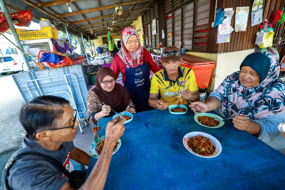 Stall owner Suriati Shairi, 41, watches as her customers enjoy ‘mi sanggul’ at her stall in Kampung Haji Hassan, Tapah Road, where the dish is sold for only RM1.50 per plate. — Bernama pic