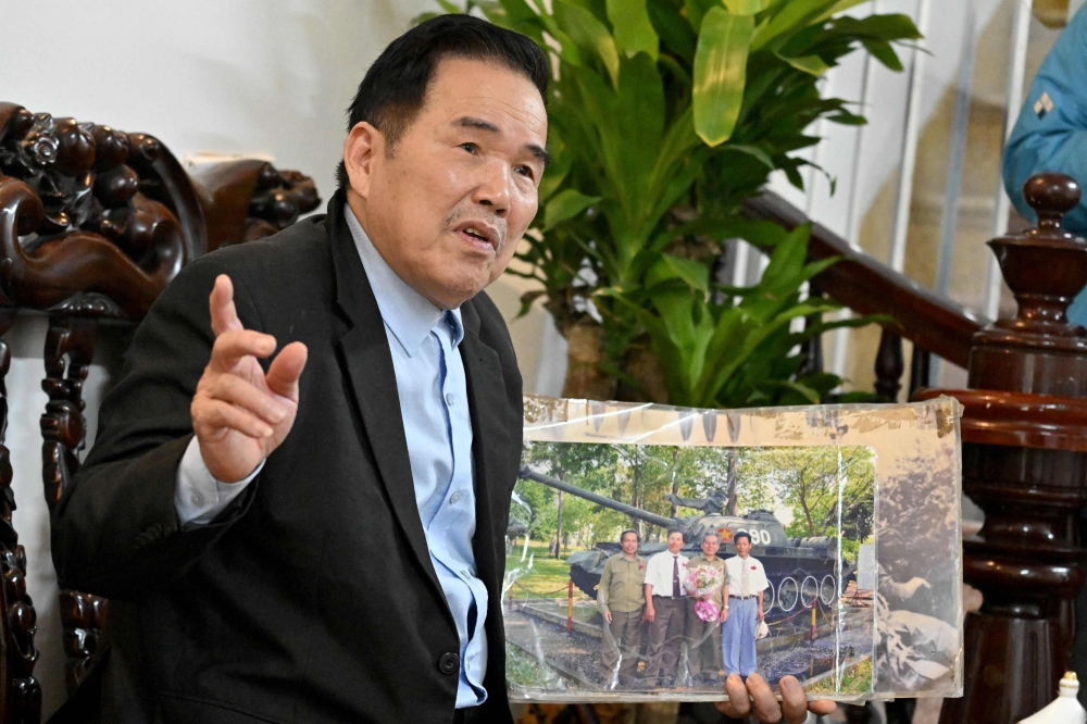 273835 Ngo Sy Nguyen, former first gunner of Tank 390, holds a photograph of himself with other members of the tank that crashed through the gates of Saigon’s presidential palace on April 30, 1975, during an interview at his home in Hanoi March 11, 2025. — AFP pic