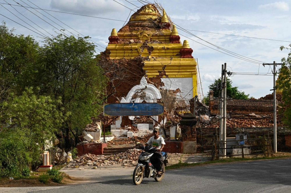 273842 A man drives his motorbike past the debris of a damaged Buddha statue in Inwa on the outskirts of Mandalay April 12, 2025, following the devastating March 28 earthquake. — AFP pic