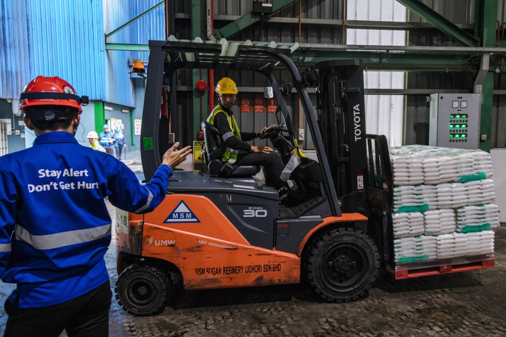 274278 An employee operates a forklift to move sacks of sugar inside a warehouse at MSM Sugar Refinery in Pasir Gudang. — Picture by Firdaus Latif