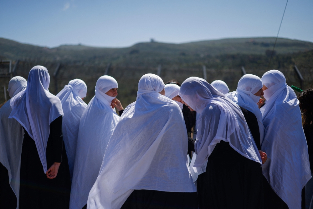 274520 Druze women await the arrival of visitng Druze dignitaries fom Syria in a bus through a border barrier guarded by Israeli soldiers, near the village of Majdal Shams in the Israeli-annexed Golan Heights, on April 25, 2025. — AFP pic