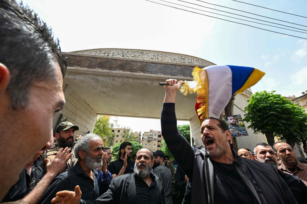 274522 Members of Syria's Druze community wave flags and chant slogans during the funeral of seven people killed during overnight clashes with Syrian security forces, in Damascus, on April 30, 2025. — AFP pic