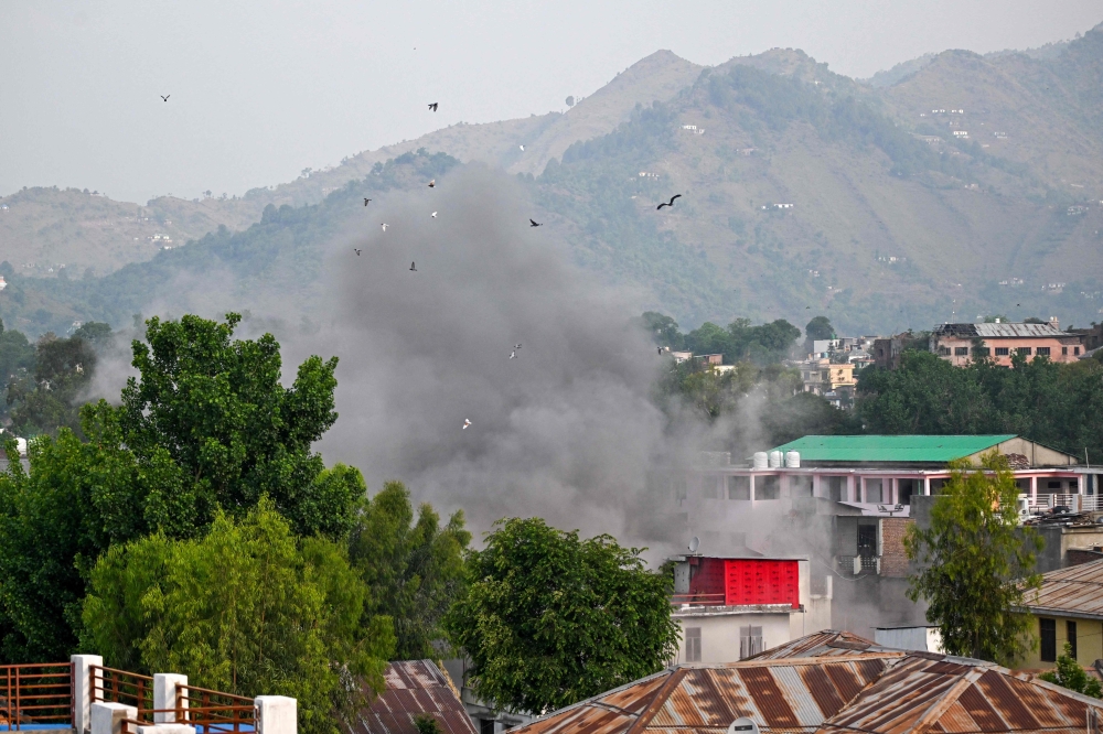 275539 Smoke billows after an artillery shell landed in the main town of Poonch district in India's Jammu region today. — AFP pic