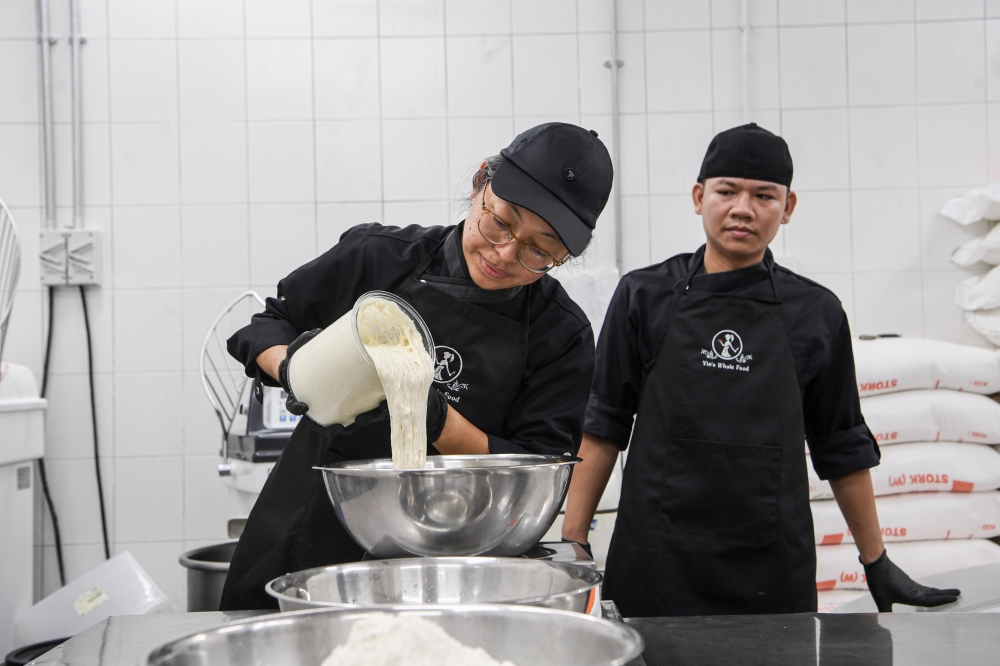 276387 Founder of Yin’s Sourdough Bakery & Cafe Chan Su Yin, 48 (left) making sourdough bread during an interview session with Bernama recently. — Bernama pic