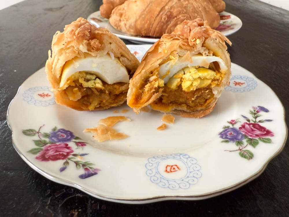 276780 A cross section of the curry puff reveals soft curried potato and chicken filling with a piece of hard boiled egg.